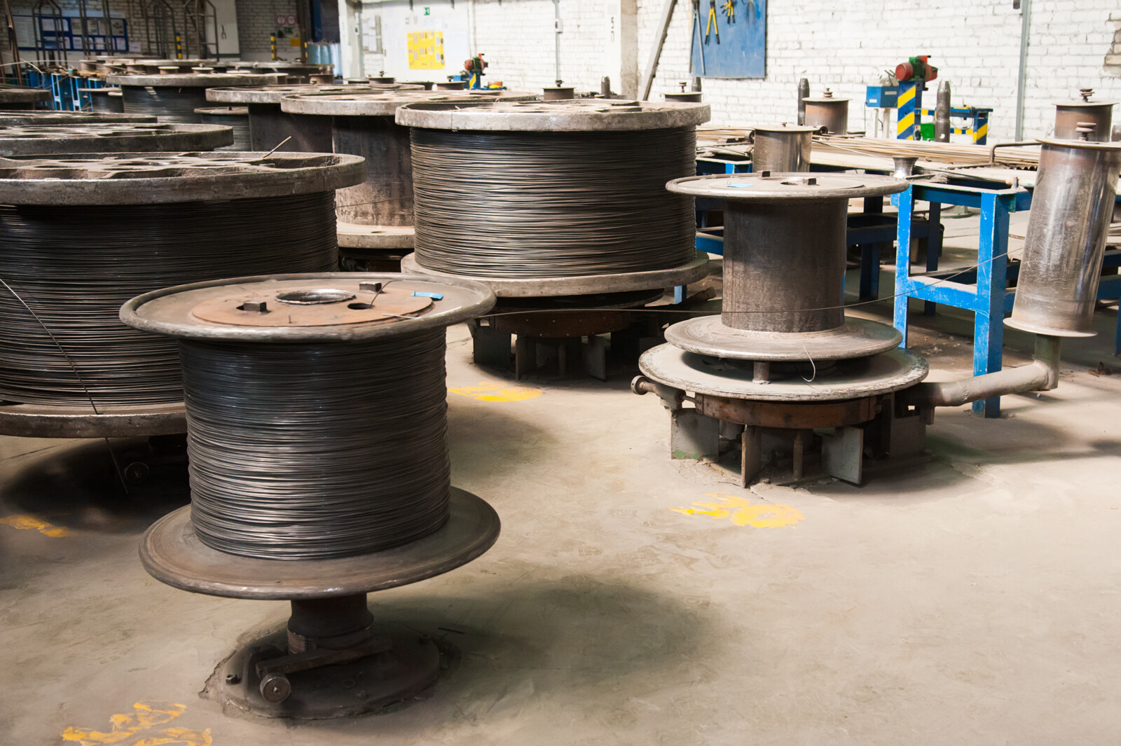 Industrial machines and coils with wire representing copper wire inventory from plant, manufacturing, or industrial electrical surplus